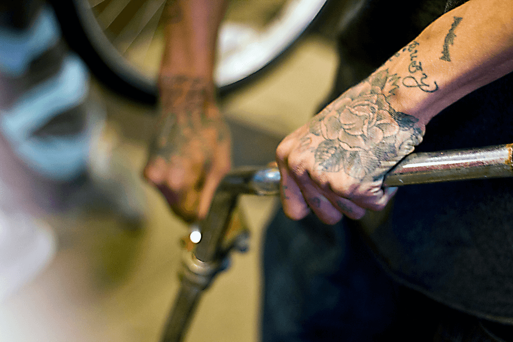 Tattooed hands tweak a bike.