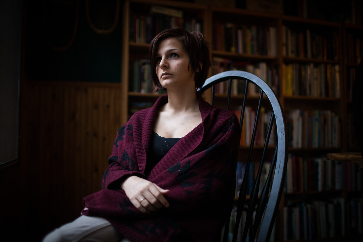 Bendell sits in chair with a book shelf behind her