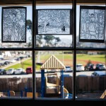 A playground is seen though a window with christian art drawings