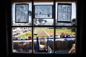 A playground is seen though a window with christian art drawings