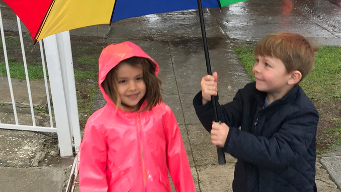 Kids in the rain under a colorful umbrella