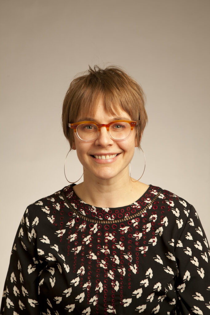 Portrait of Katie Miller, a woman with short auburn hair and a black top.