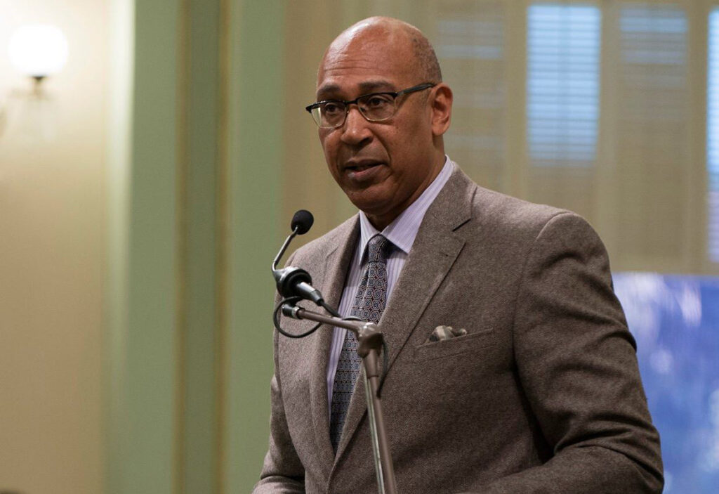 California Assemblymember Chris Holden, pictured in a brown seat speaking into a microphone, has authored a bill that would ban police from lying to minors during interrogations