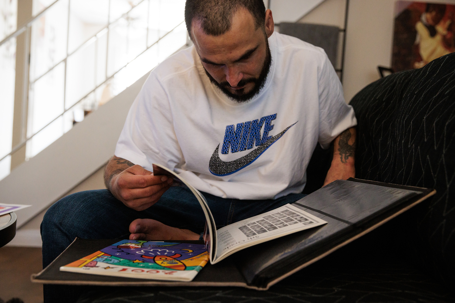 A man wearing a white and blue Nike shirt looks through old yearbooks.