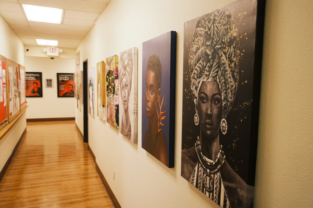 A hallway with paintings lining the walls at Rose Family Creative Empowerment Center.